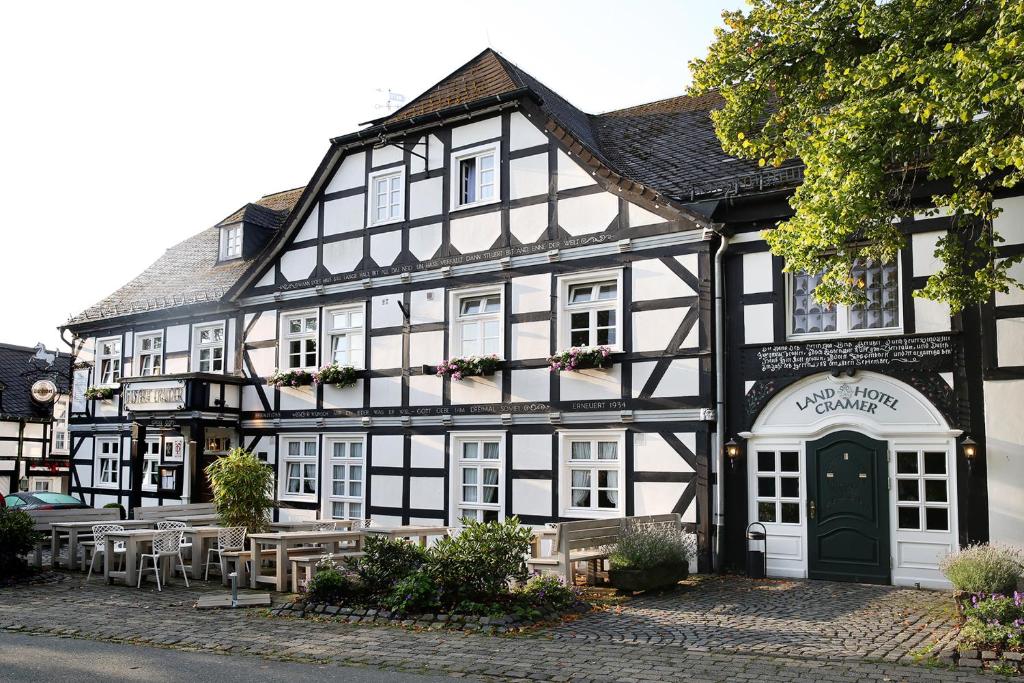 un bâtiment noir et blanc avec des tables devant lui dans l'établissement Landhotel & Gasthof Cramer, à Warstein