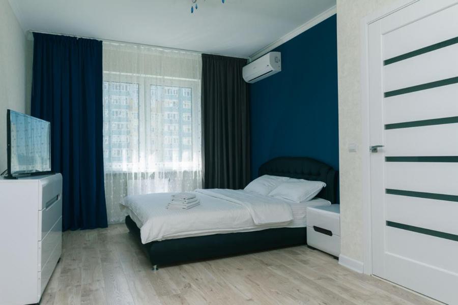 Schlafzimmer mit einem Bett mit blauen Wänden und einem Fenster in der Unterkunft Софии Русовой 7 in Kiew