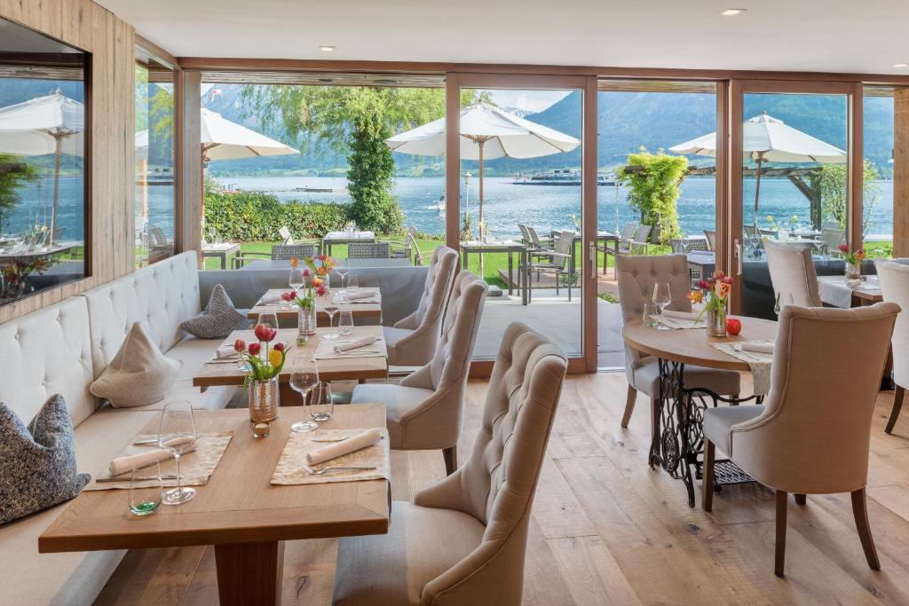 a restaurant with tables and chairs and windows at Hotel Seevilla Wolfgangsee in St. Wolfgang