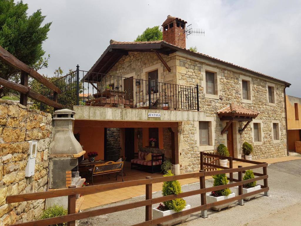 een groot stenen huis met een veranda en een balkon bij Casa Rural Juntana in Abionzo