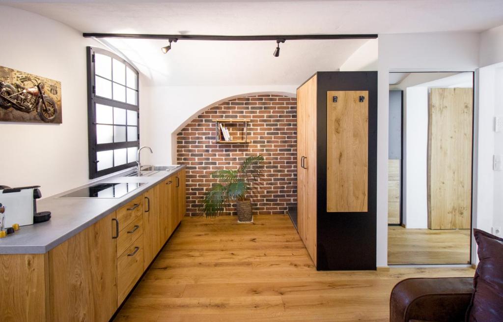 a kitchen with wooden cabinets and a brick wall at DAREBELL Loft Gratkorn Top 1 in Gratkorn