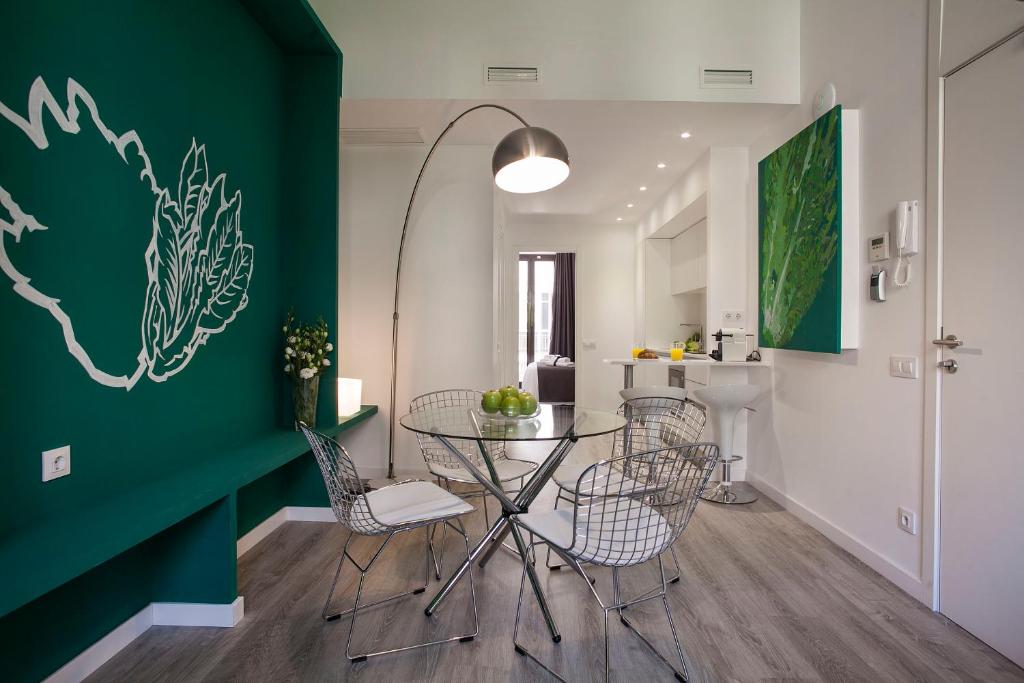 una sala da pranzo con parete verde e tavolo e sedie di Habitat Apartments ADN a Barcellona
