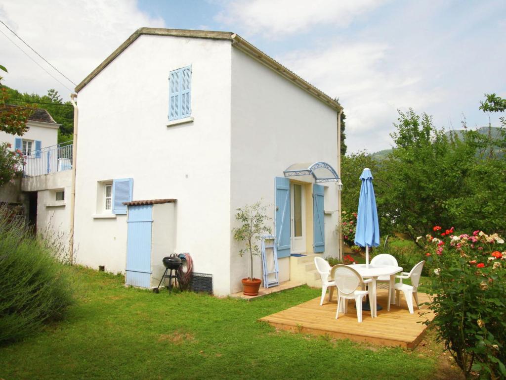 a white house with a table and chairs and an umbrella at Tranquil Holiday Home in Corsica with Terrace in Penta-di-Casinca