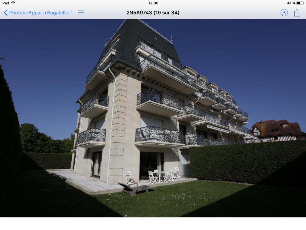 a large building with a balcony and tables and chairs at Deauville rez de jardin/Garden Floor in Deauville