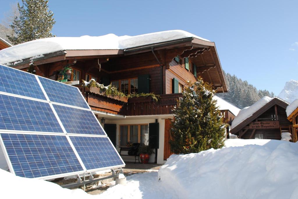 a house with a solar panels in the snow at Apartment Nadeschda in Adelboden