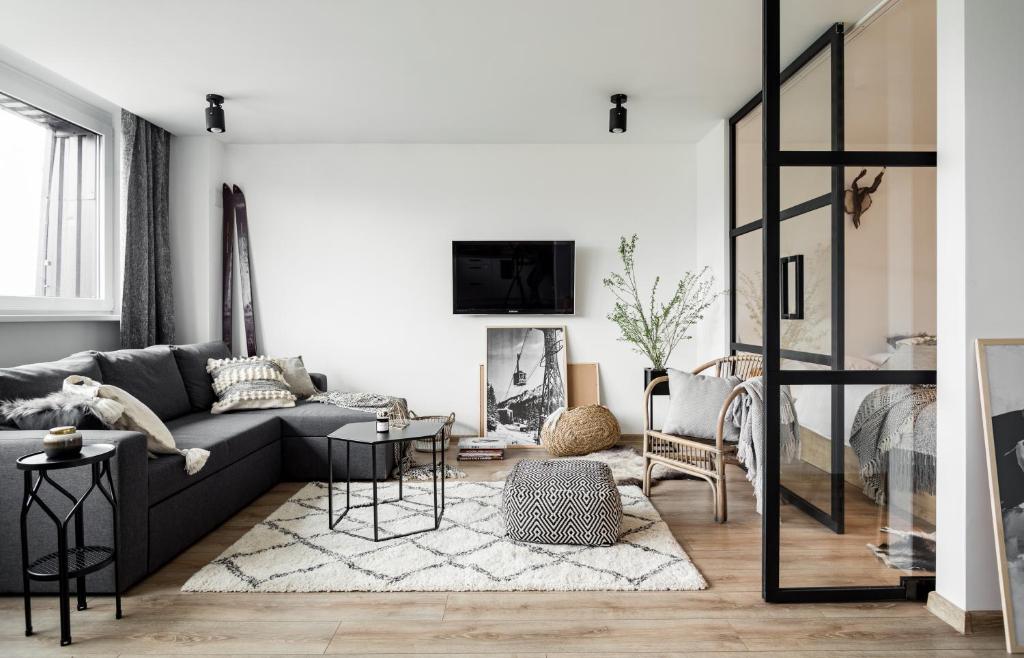 a living room with a gray couch and a fireplace at udanypobyt Smrekova Apartament in Zakopane