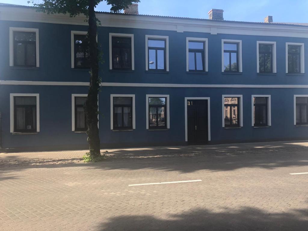 een blauw gebouw met een boom ervoor bij Viesu nams Stella in Ventspils