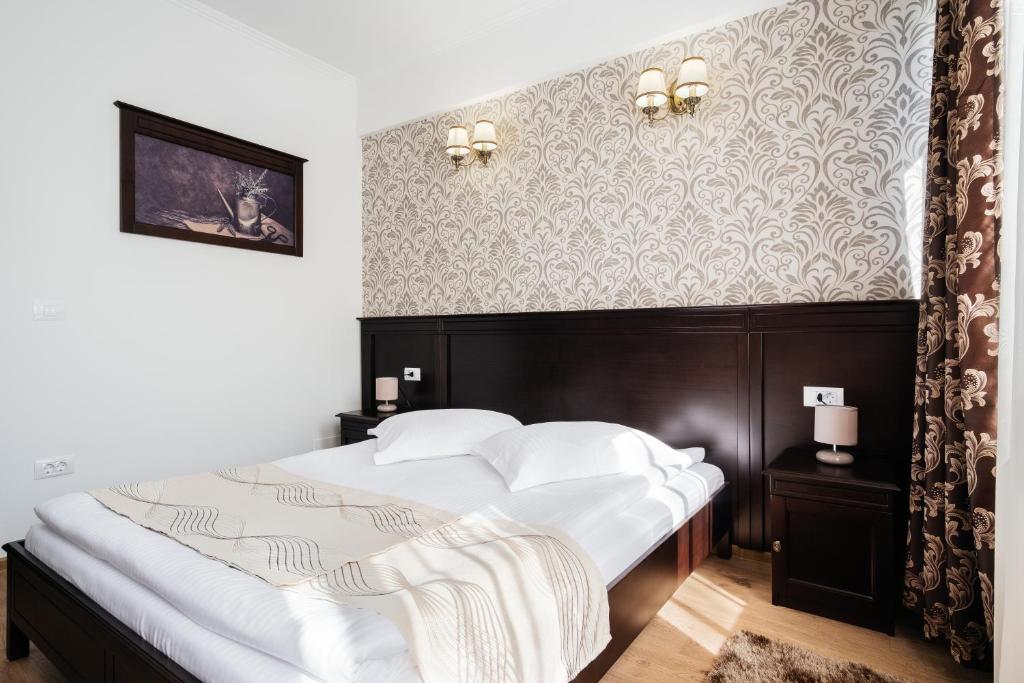 a bedroom with a large bed with white sheets at Hotel Turist in Fălticeni