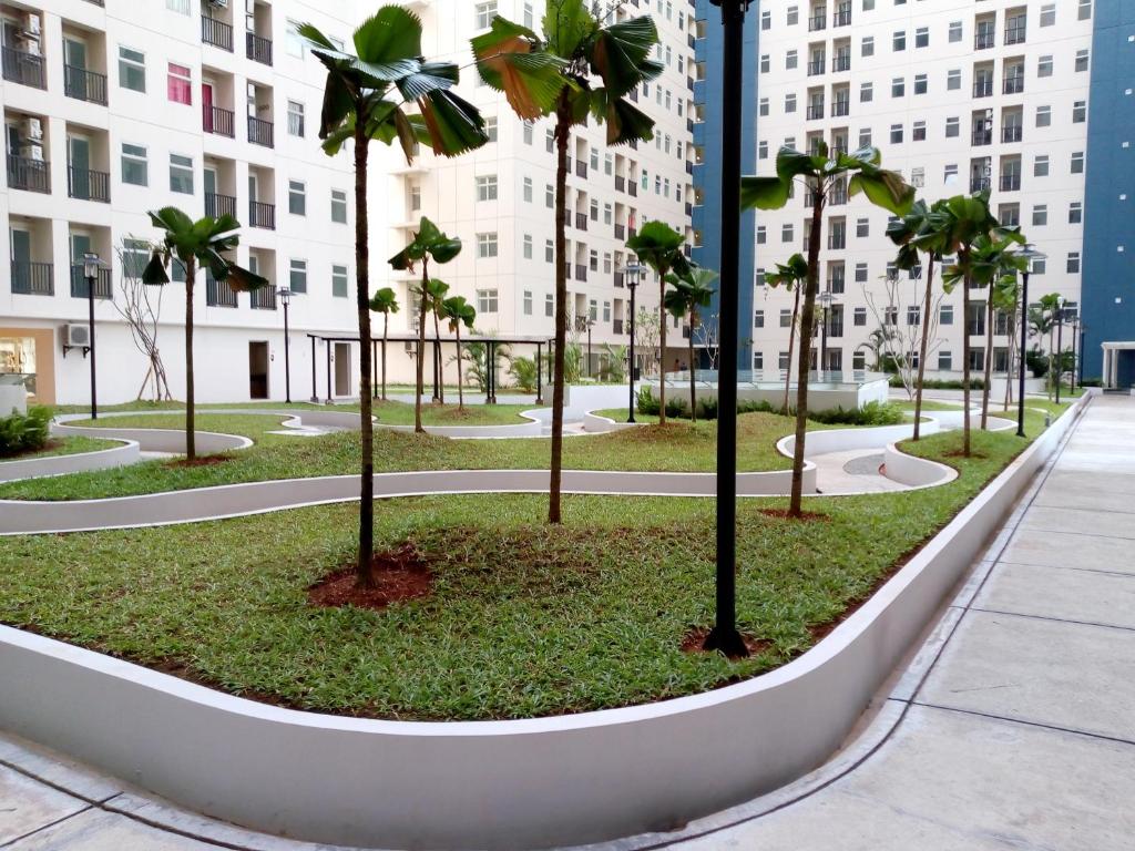 un parc avec des palmiers en face d'un bâtiment dans l'établissement Apartment Kota Ayodhya - Christine, à Tangerang