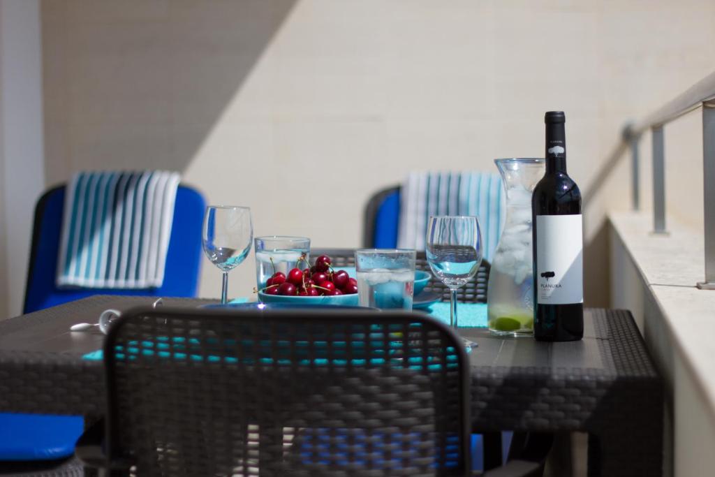 a table with a bottle of wine and a bowl of fruit at Monte da Eira in Albufeira