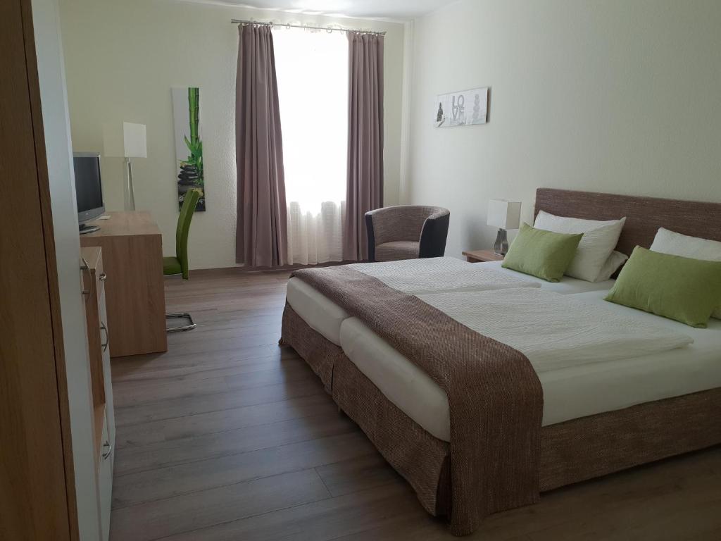 a bedroom with a large bed with green pillows at Hotel Hof Münsterland in Ahlen