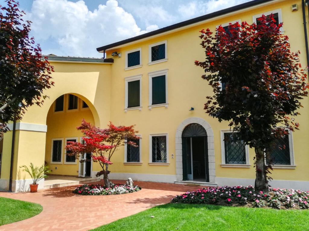 una casa gialla con due alberi in un cortile di Villa Montenero a Cavalcaselle