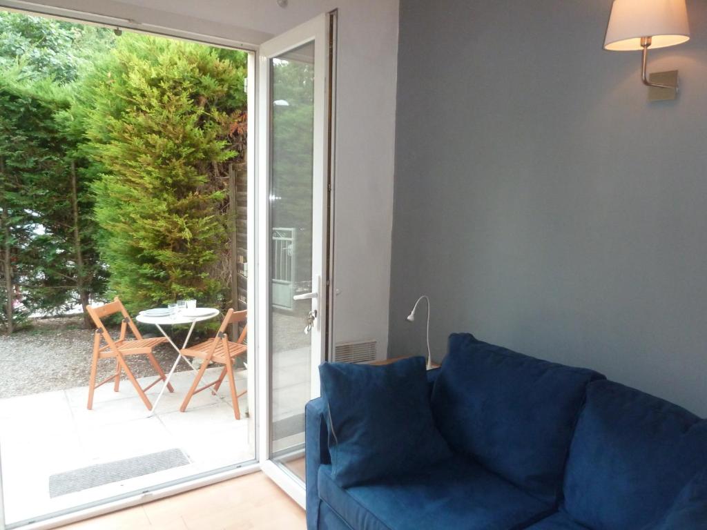 een blauwe bank in een woonkamer met een glazen schuifdeur bij Petit Studio, terrasse, jardinet, climatisation, wifi in Nice