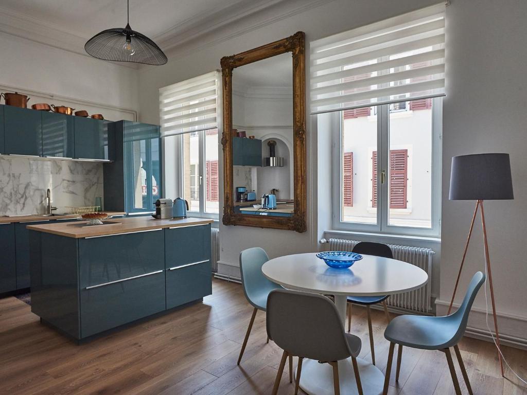 Una cocina con gabinetes azules y una mesa y sillas. en Les Appartements Saint-Martin, en Colmar