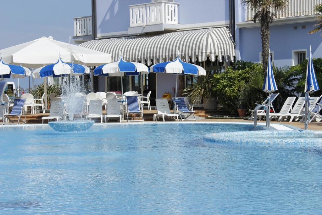 una piscina con sombrillas y sillas azules y blancas en Hotel Principe, en Caorle