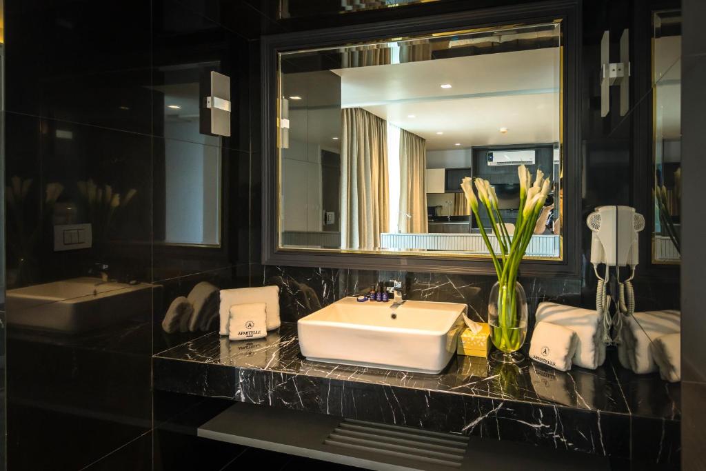 A dark marble bathroom vanity with a vessel sink, mirror and hotel amenities.