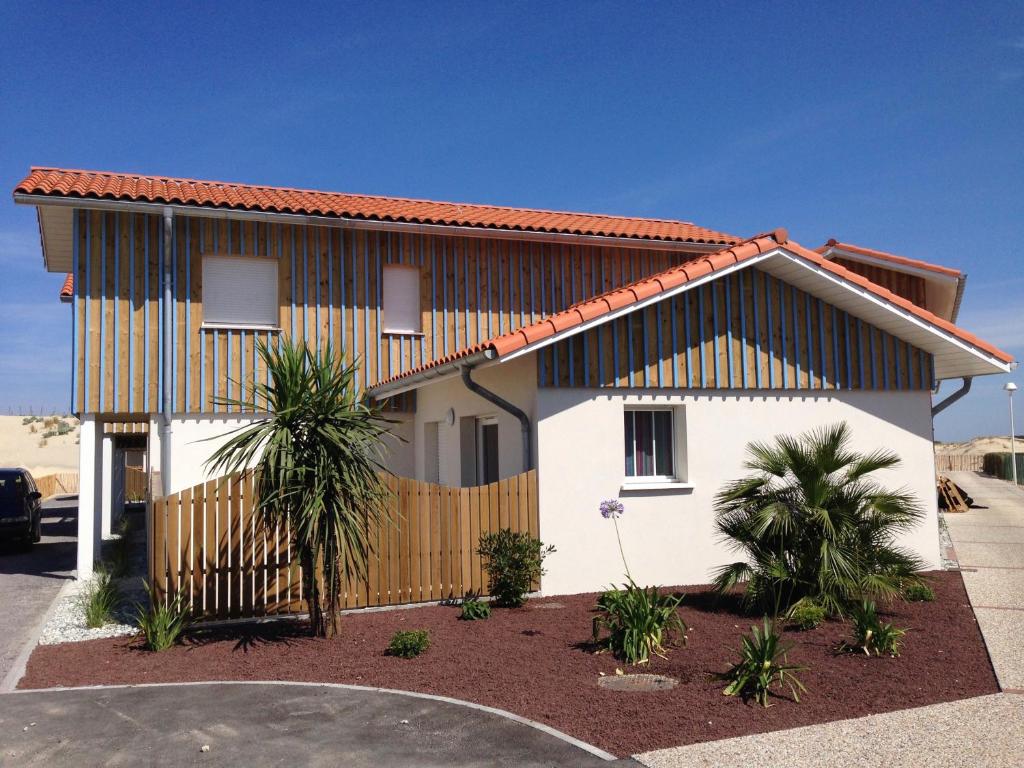 a white house with a fence and palm trees at Residence Plage Oceane in Biscarrosse-Plage