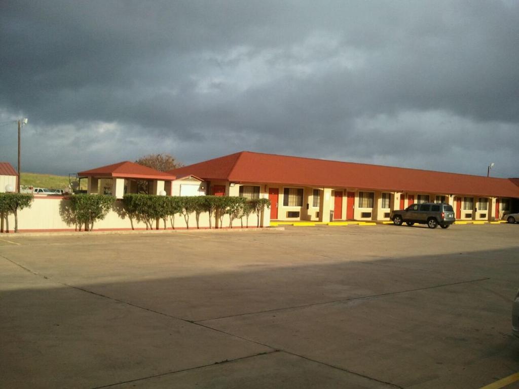 un edificio con un camion parcheggiato in un parcheggio di Royal Inn Pearsall a Pearsall