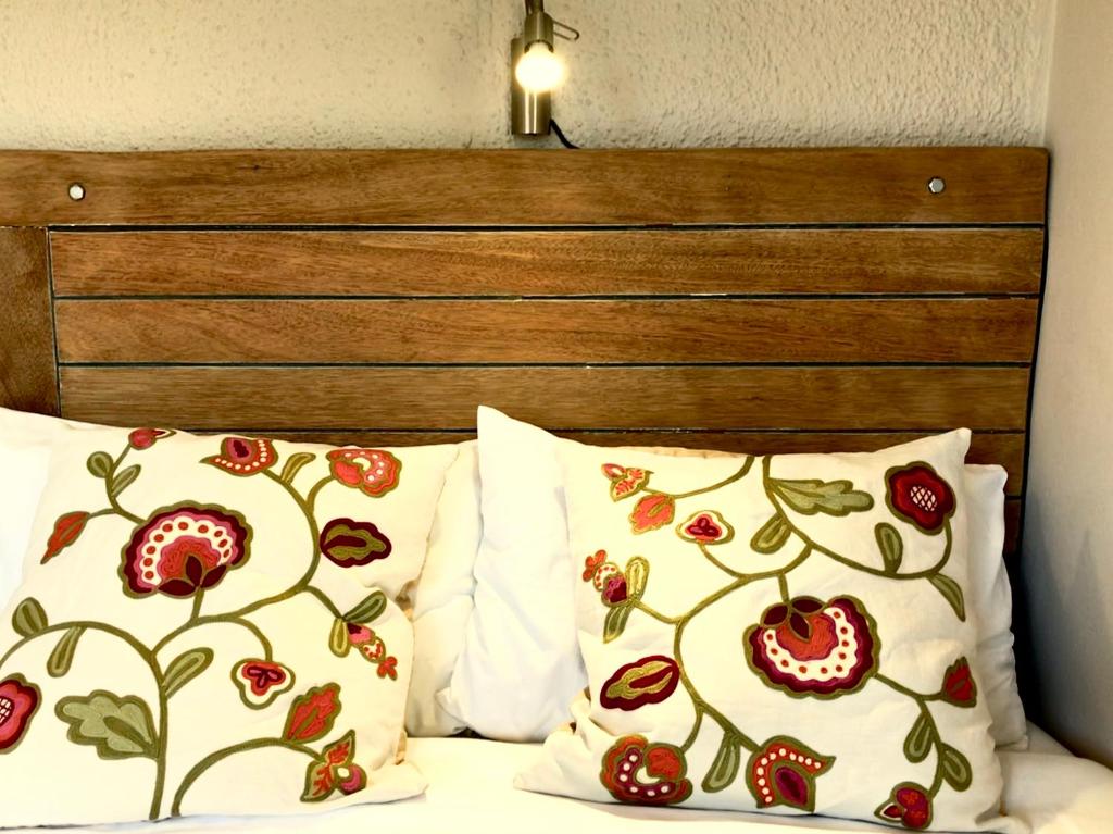 a bed with two pillows and a wooden headboard at Settlers Valley Cottage in Port Elizabeth