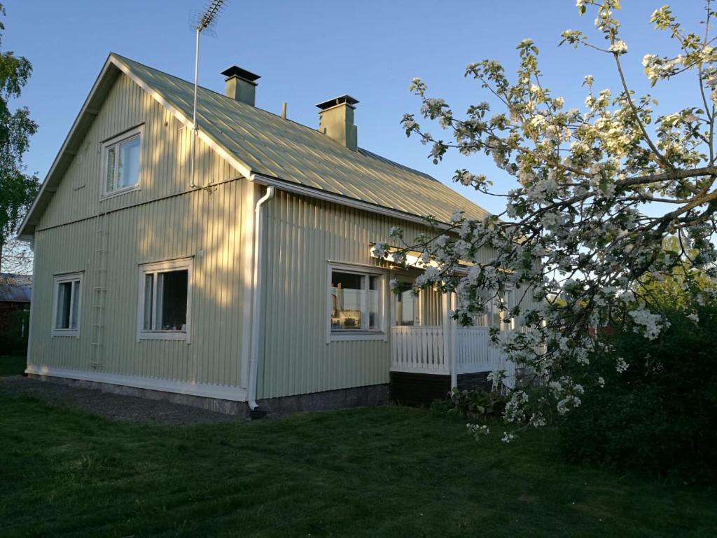 uma pequena casa branca com uma árvore no quintal em Willa Mustijoki em Laukkoski
