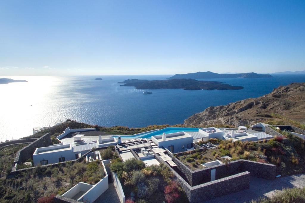 an aerial view of a resort on a hill with the ocean at Erosantorini Luxury Private Estate & Suites in Fira