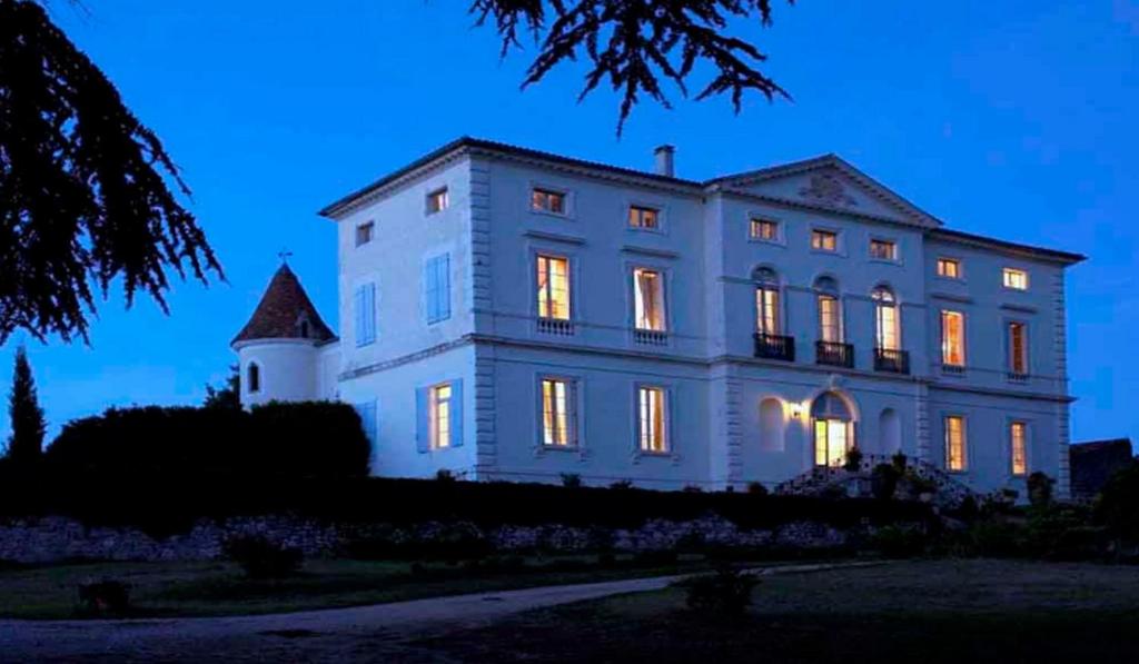 una gran casa blanca con sus luces encendidas en Chambres d'Hôtes du Chateau de Saint Sulpice, en La Sauvetat-sur-Lède