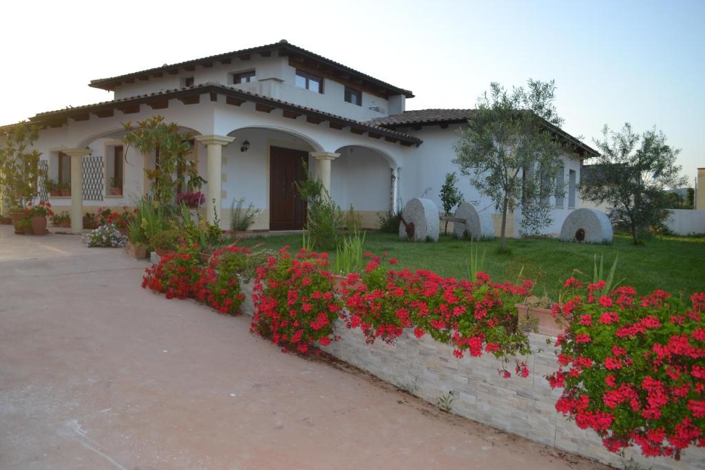 una casa con fiori rossi davanti di I Giganti a Riola Sardo