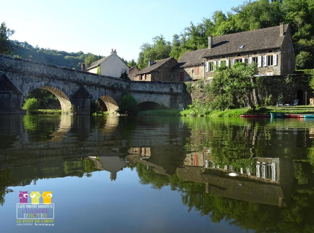 un vieux pont sur une rivière avec des maisons et des arbres dans l'établissement Les Trois Hiboux, à Crespin