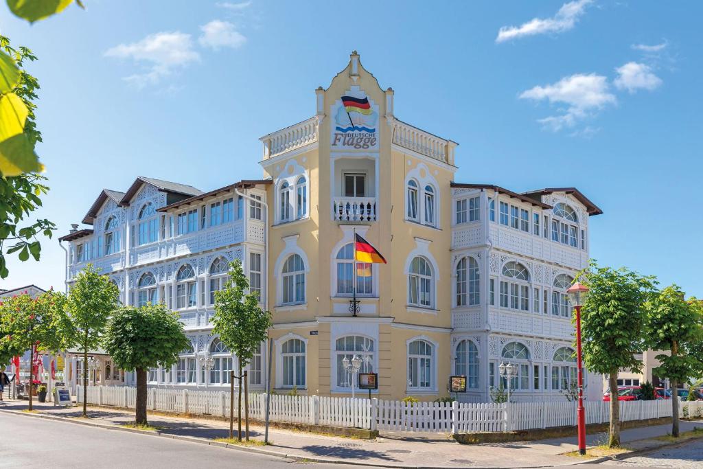 um edifício amarelo e branco com uma cerca branca em Hotel Deutsche Flagge em Binz