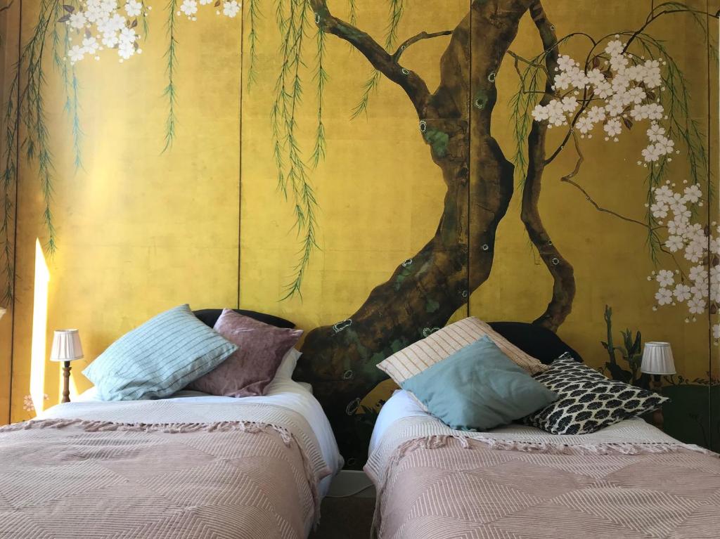 twee bedden in een kamer met een muurschildering van bomen bij B&B Valkenbos in Den Haag