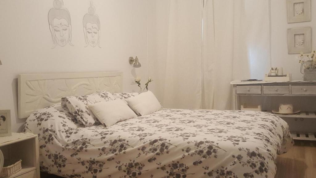 a white bedroom with a bed with a floral comforter at Fonda Felip in Port de la Selva