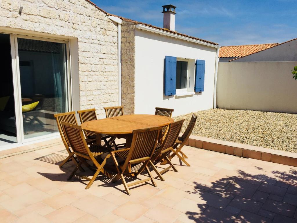 a wooden table and chairs on a patio at Cosy villa La Garancière - Plein coeur de la Cotinière in La Cotinière