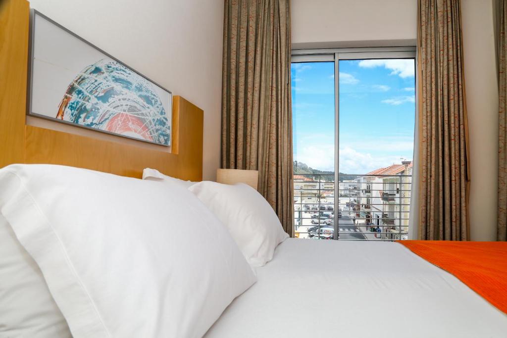 a hotel room with a bed and a large window at Hotel Praia in Nazaré