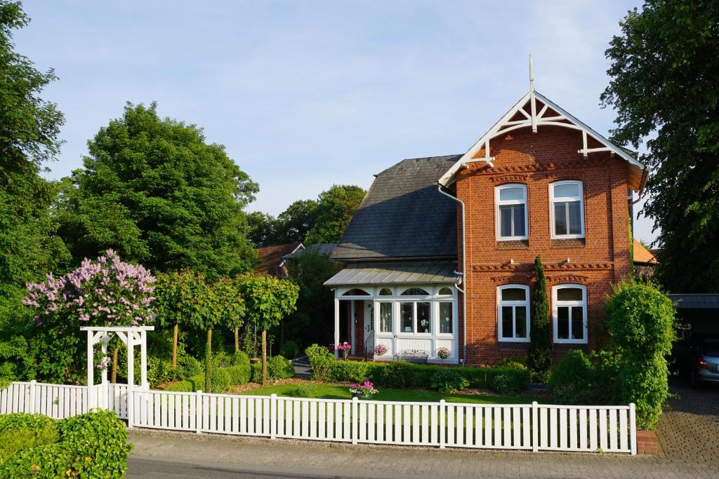 una casa de ladrillo rojo con una valla blanca en Villa Wilhelmina, en Hemmoor
