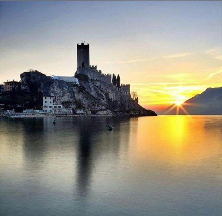 a castle on an island in the water at sunset at casa caberlon in Malcesine