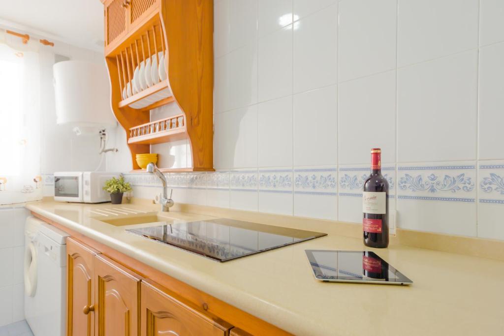 a kitchen with a sink and a bottle of wine at Apartamentos Sanlúcar &amp; Doñana in Sanlúcar de Barrameda
