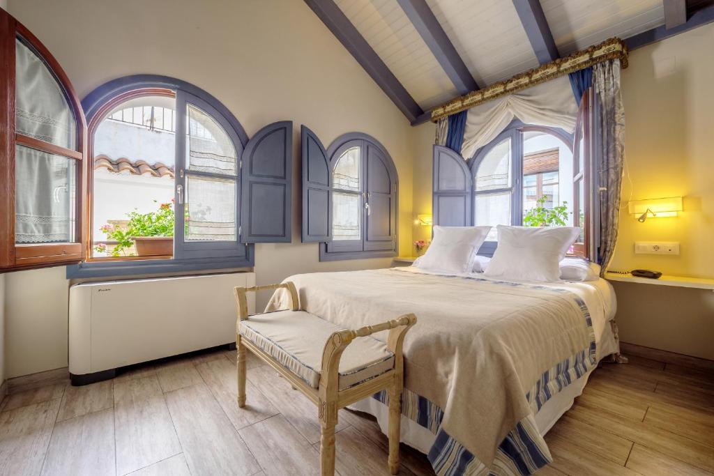 a bedroom with a bed and a chair and windows at ApartaSuites Alberca Deluxe in Córdoba