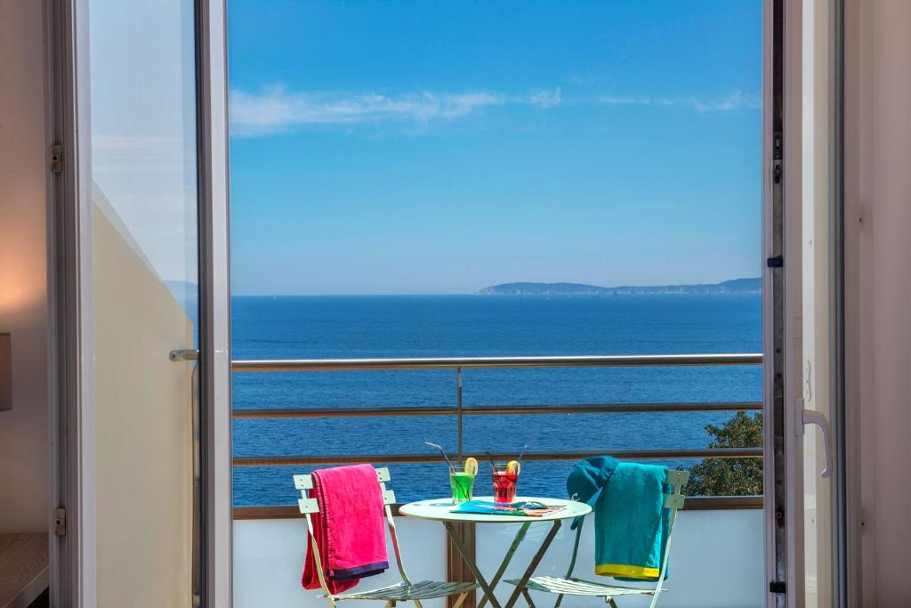 uma mesa e cadeiras numa varanda com vista para o oceano em Hôtel-Club du Domaine d'Aiguebelle, USSIM Vacances em Le Lavandou