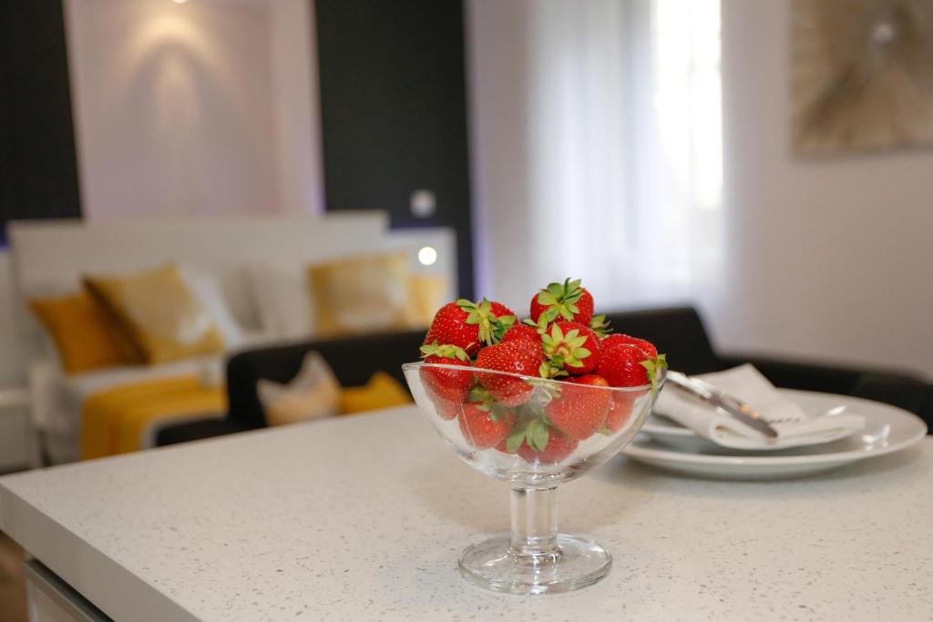 a bowl of strawberries on a counter with a plate at Studio Apartman Fictilis in Split