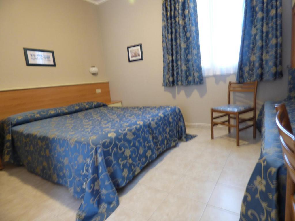 a hotel room with a bed and a chair at Hotel Turandot in Torre del Lago Puccini