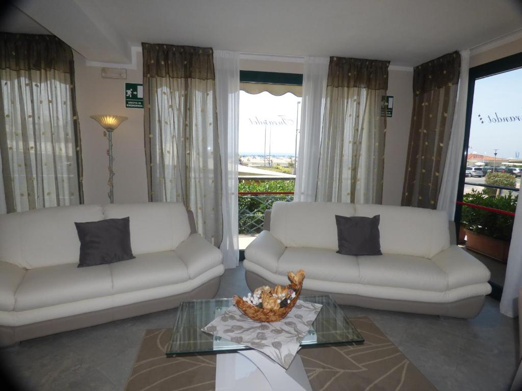 a living room with two white couches and a glass table at Hotel Turandot in Torre del Lago Puccini