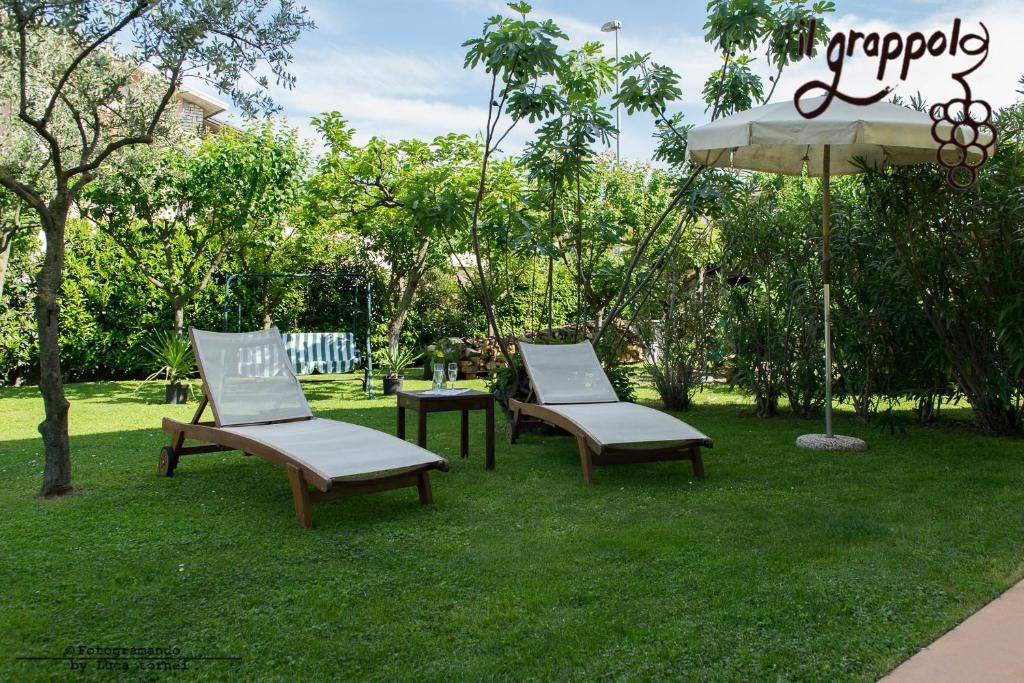 西爾米奧奈的住宿－B&b Il grappolo Foresteria Lombarda，草地上的两把椅子和一把伞