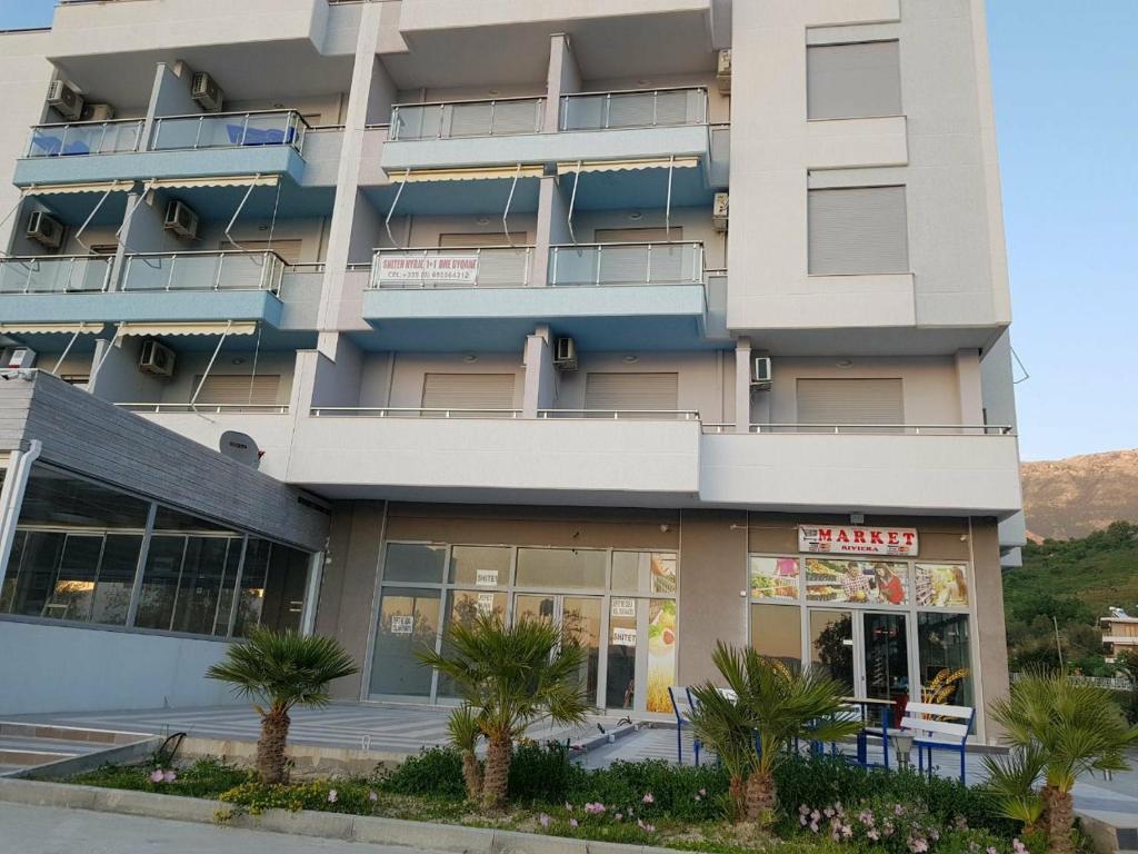 a building with palm trees in front of it at Apartamente-Danaj Radhime in Vlorë
