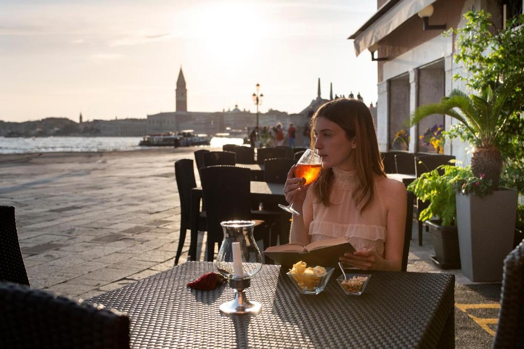 
a woman sitting at a table with a glass of wine at Hotel Bucintoro in Venice
