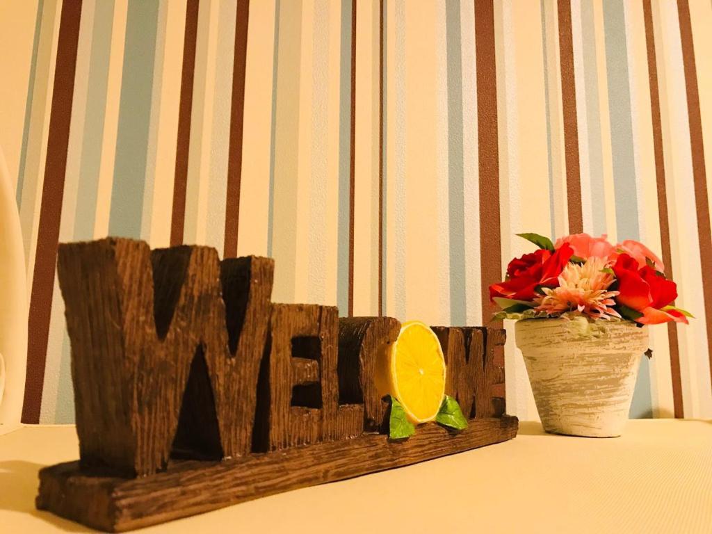 a wooden sign that says war next to a vase of flowers at nestay inn tokyo senju in Tokyo