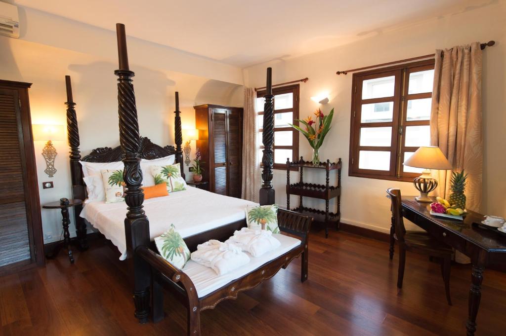 a bedroom with a bed and a desk and a table with towels at Hotel l'Impératrice in Fort-de-France