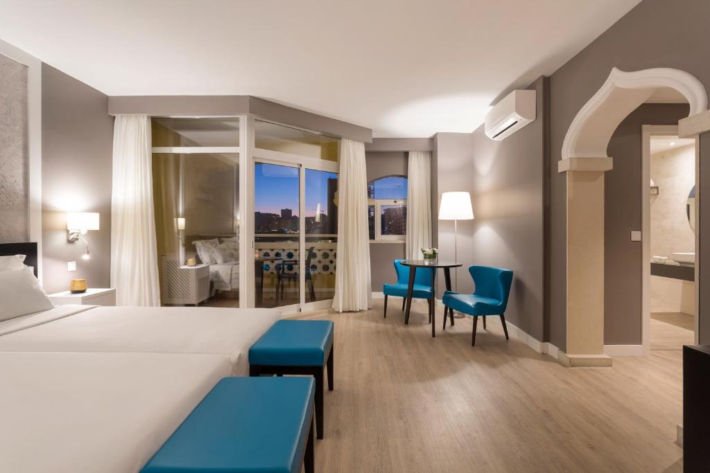 a hotel room with a bed and a table with chairs at AP Oriental Beach - Adults Friendly in Portimão
