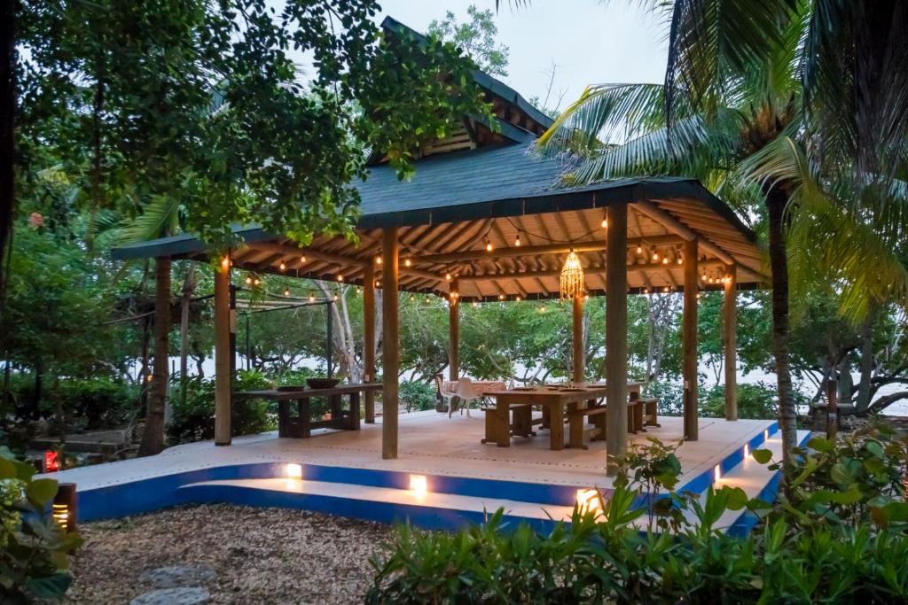 a wooden gazebo with a picnic table and benches at Hotel Playa Manglares Isla Baru in Baru