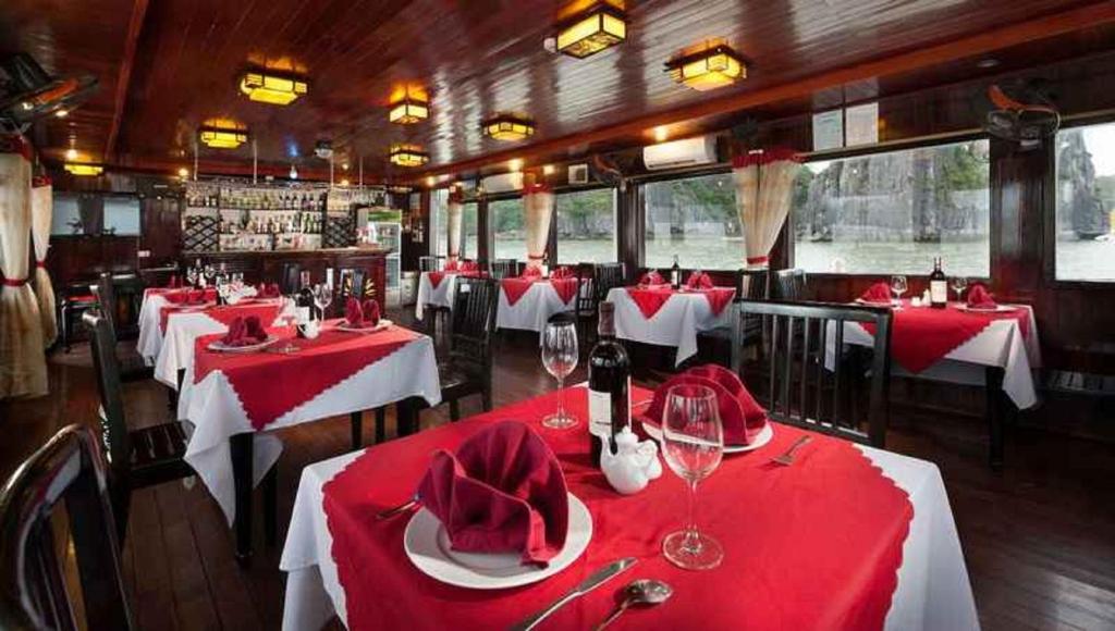 a restaurant with red and white tables with wine glasses at Fantasea Imperial Cruise in Ha Long