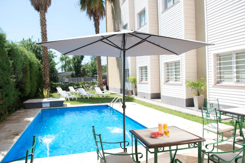 a table with an umbrella next to a pool at Hathor Hotels Mendoza in Mendoza